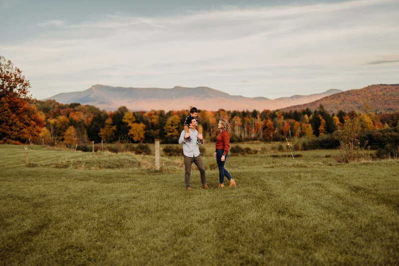 A candid family moment full of laughter, set against the vibrant fall colors of a Vermont field.