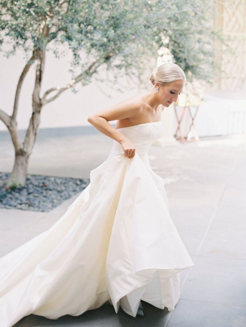 Bride walking while holding up the hem of her dress