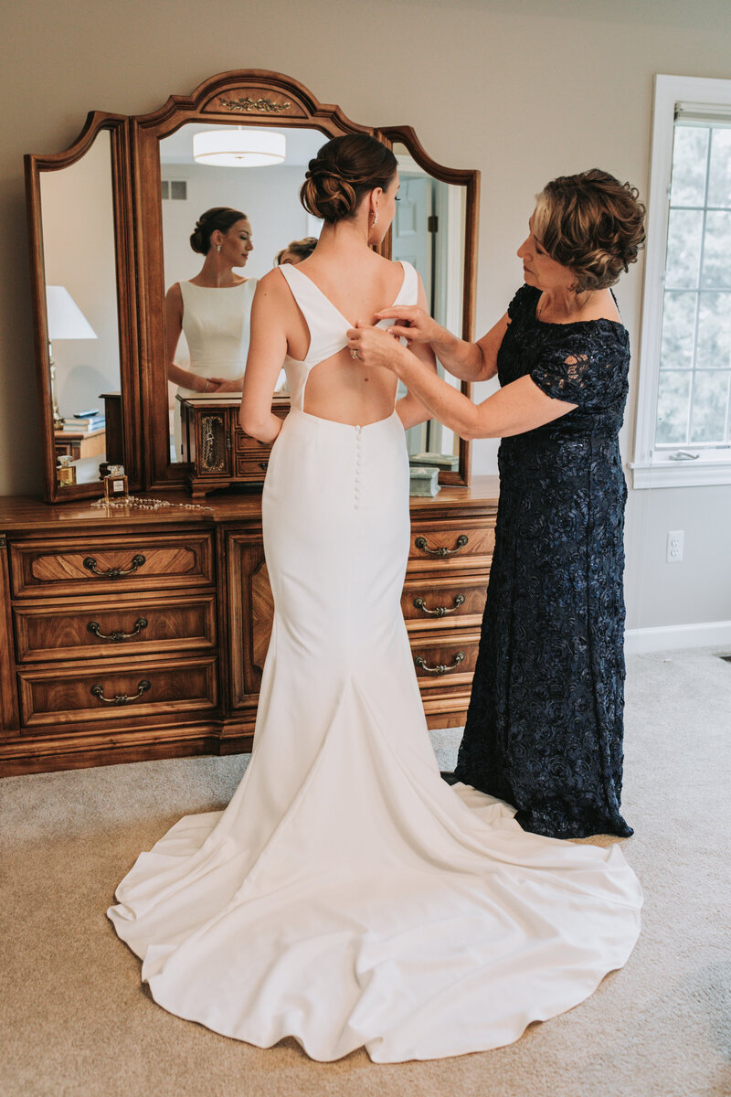 Mother of the bride helping the bride put her dress on