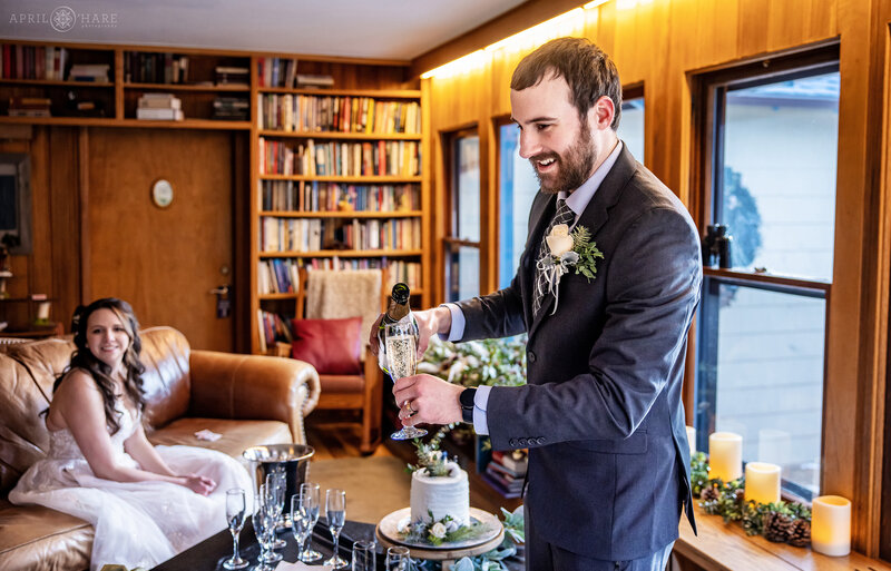 Groom Pours Champagne inside the living room at Romantic Riversong Inn Estes Park Wedding