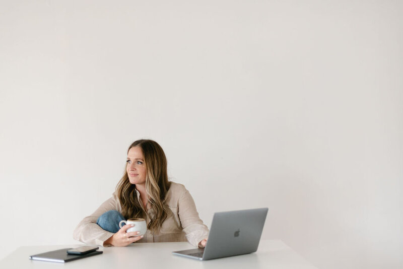 Woman smiling and holding a cup of coffee at a desk