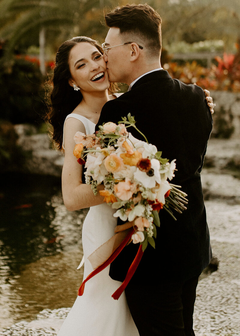 Sebastian putting a big ol smooch on the smiling cheek of Bianca.