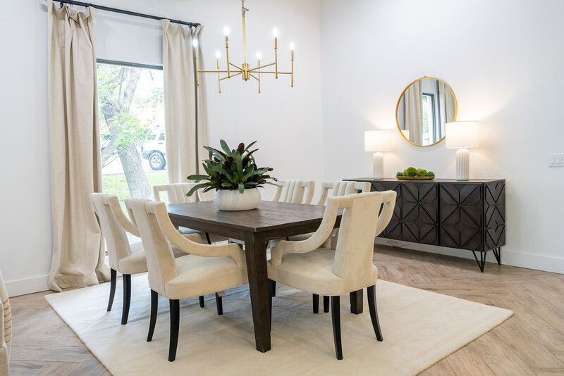 dining table with white chairs, green plant, gold accents