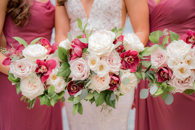 bride and bridesmaids holding blush and burgundy bouquets
