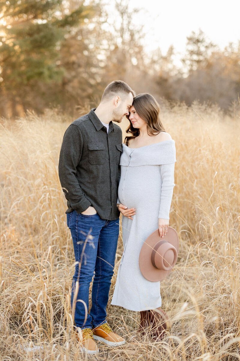 Expecting parents touching foreheads in a golden field, taken by newborn photographer minneapolis, minneapolis