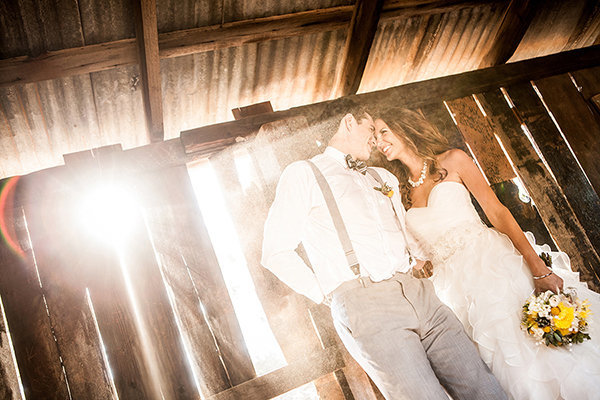 couple holding each other at a barn venue with incredible light taken by ABM Photography