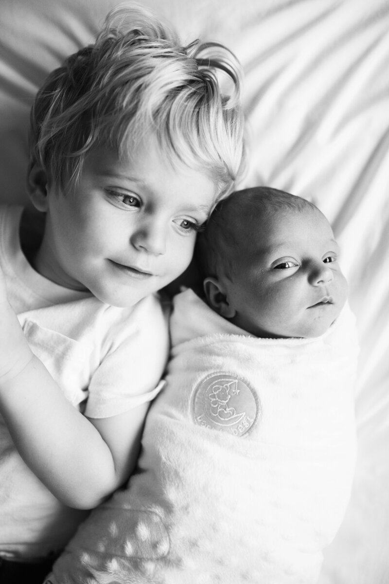 Black and white newborn photo of baby with big brother