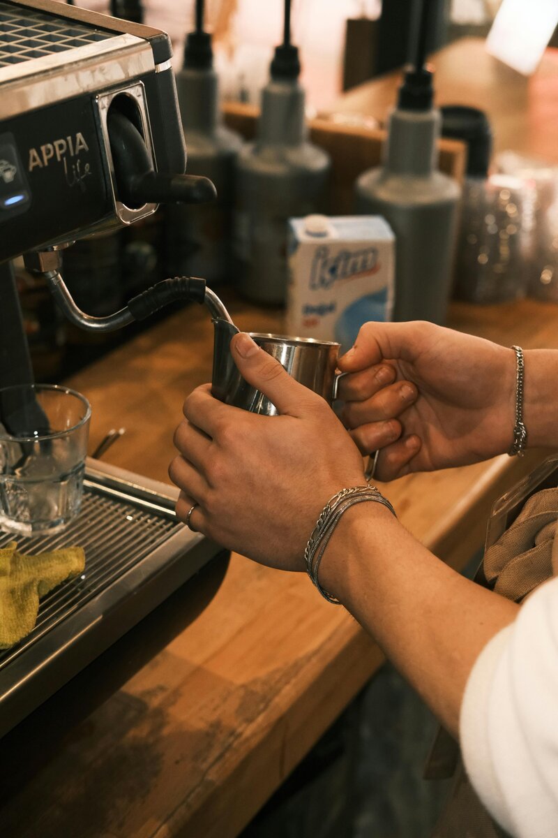hands frothing a cup of milk