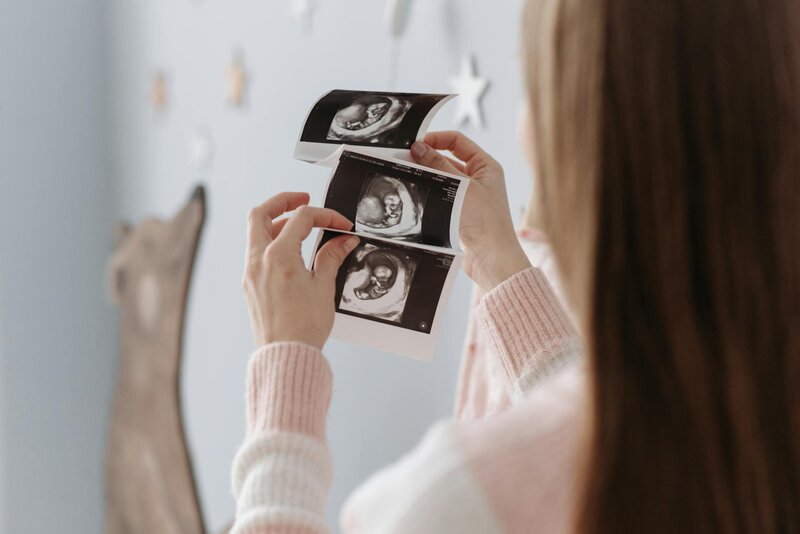 Hands holding ultrasound photos, representing a traumatic birth story and journey toward postpartum healing