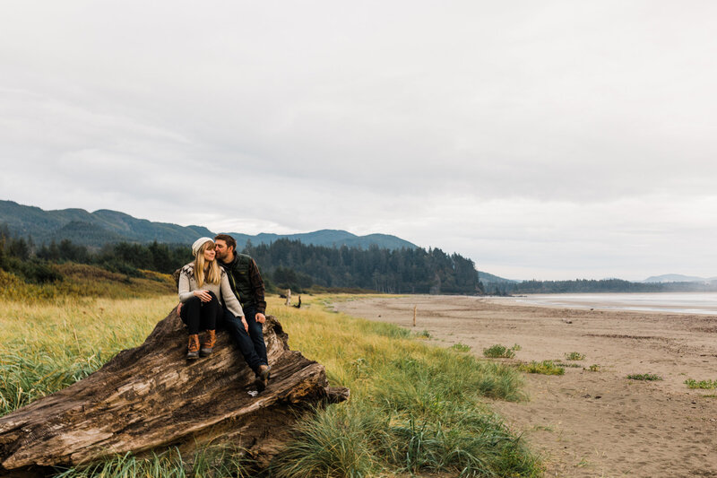 a couple sits on a lot on the beach on the north Washington coast near olympic national park