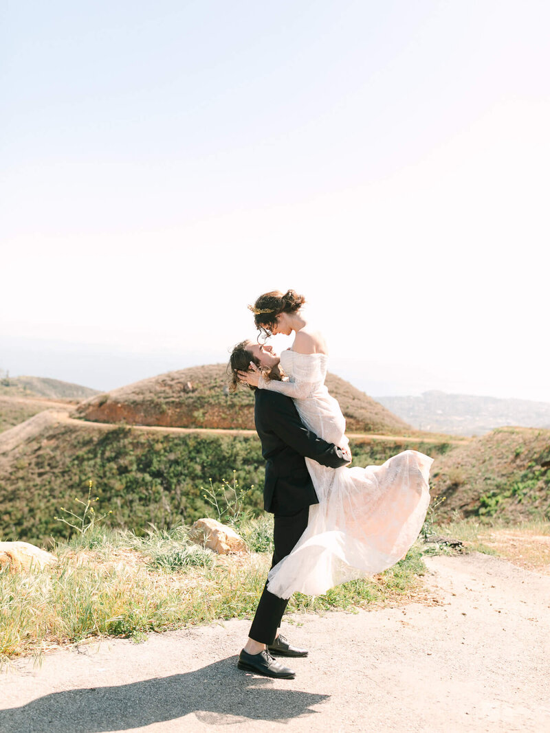 sunset wedding photography of bride and groom hugging overlooking a cliff