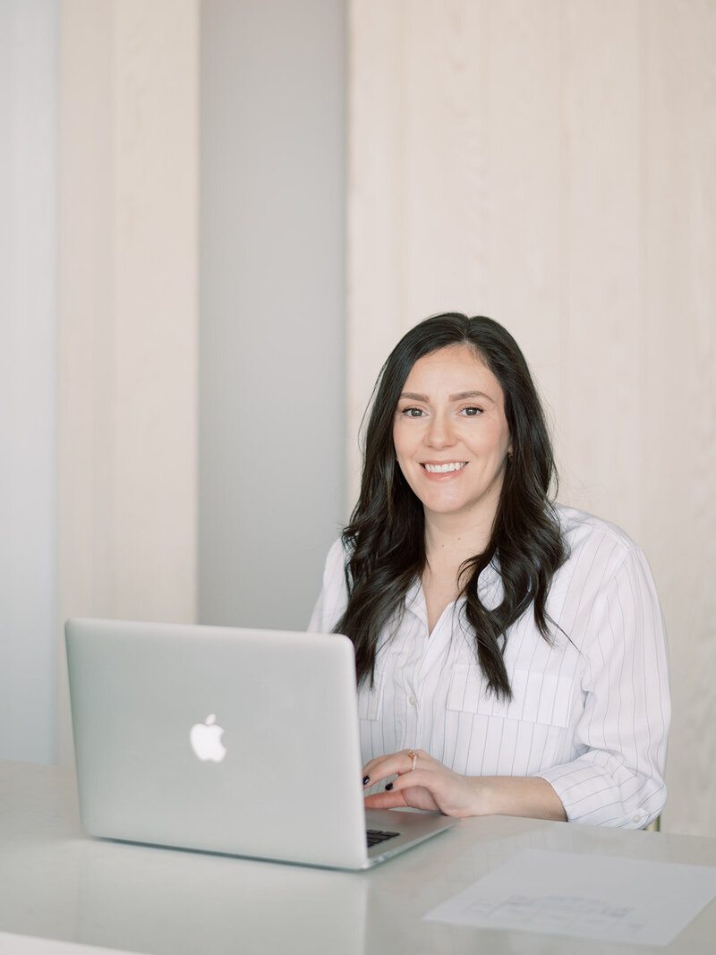 A corporate eventplanner and designer sitting at a desk with her laptop.