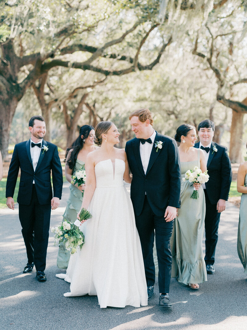 Bride and groom holding hands and walking with bridal party outside