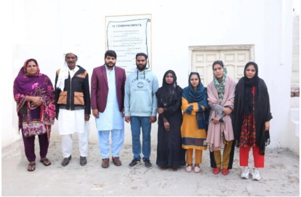 Paid on-site team stands in front of the school where they serve the children.