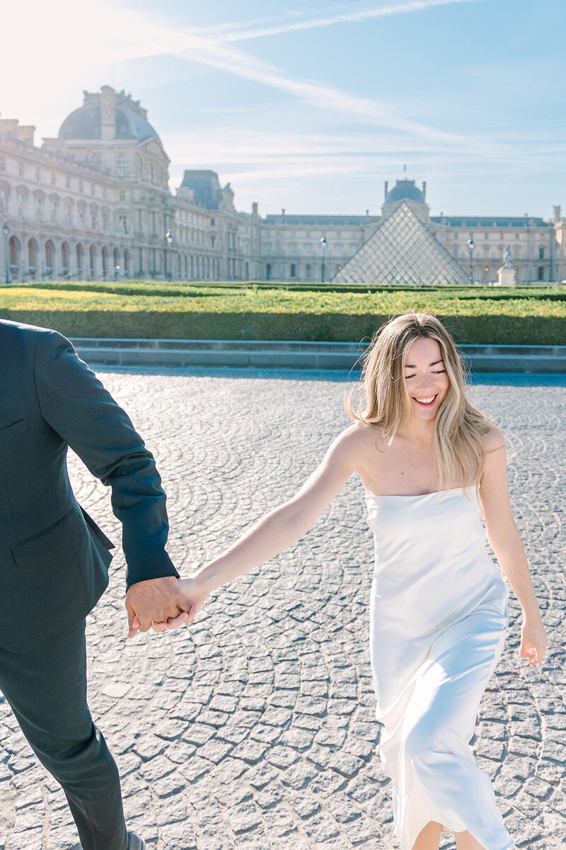 Couple laughing and holding hands during a romantic Paris photoshoot near the Eiffel Tower and Tuileries Garden.
