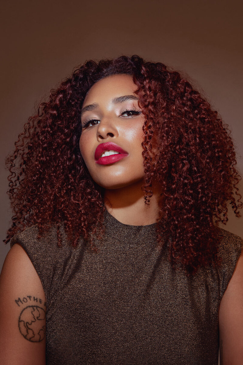 Vibrant portrait of Jazz Walters with voluminous curly hair and bold makeup, captured by Ylva Erevall.