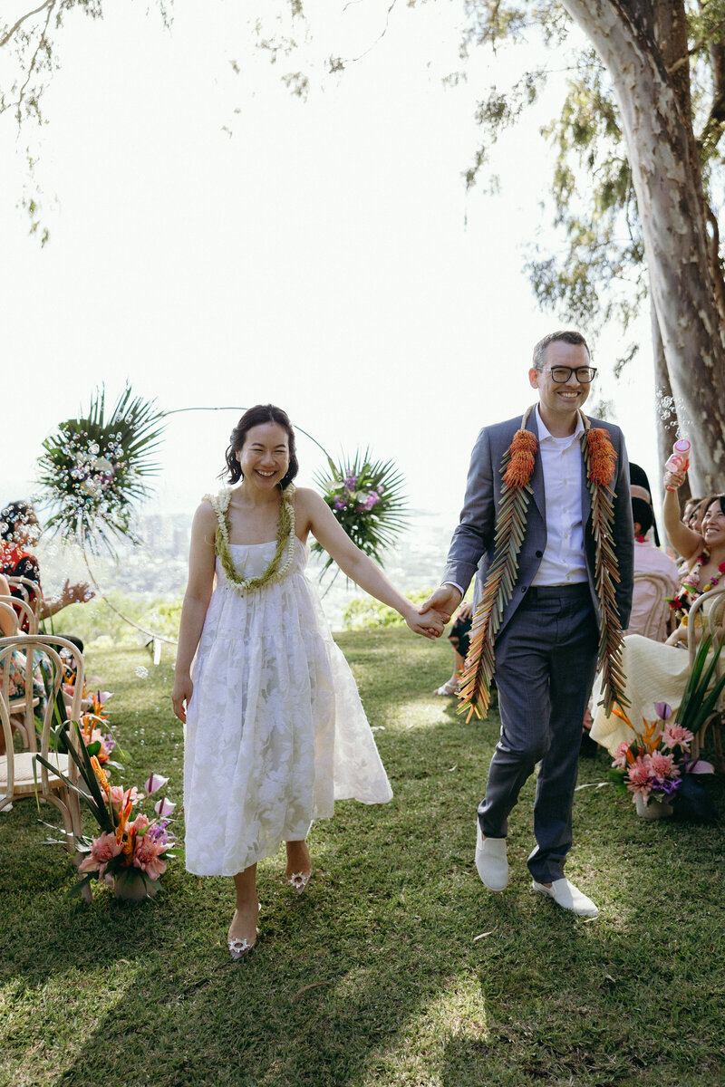 Bride twirling in silk gown with groom watching at Kualoa Ranch