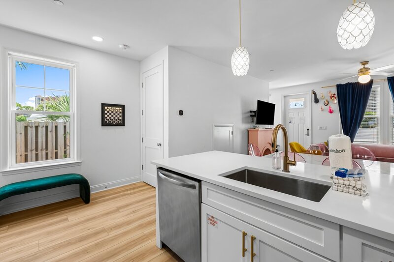 Bright and open kitchen with brass faucet and view of colorful living area—perfect setup for entertaining during your Panama City Beach getaway.