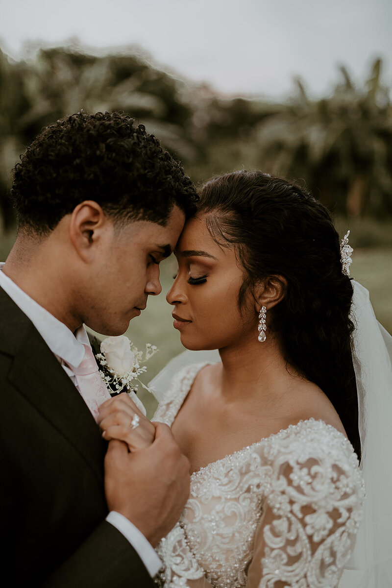 Bride and groom leaning foreheads close together and holding hands