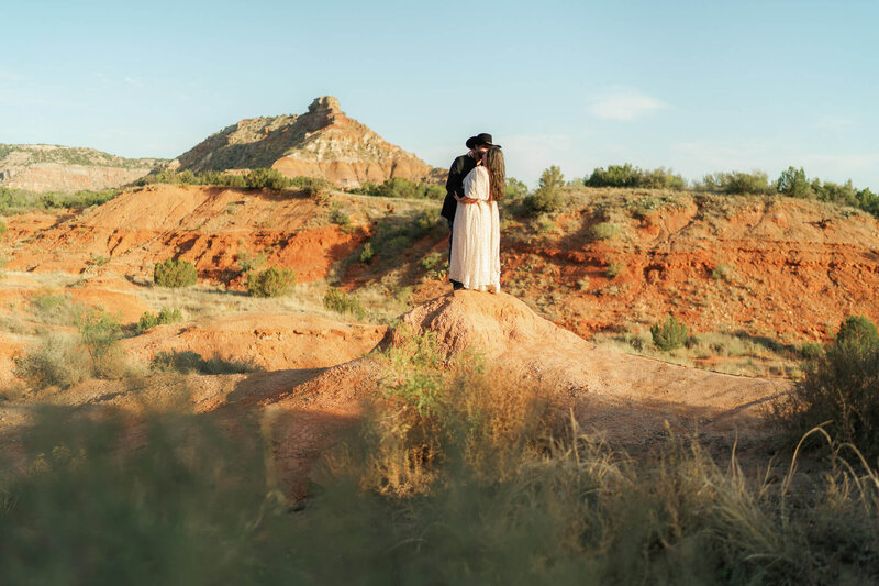 bride and groom kiss on top of a mound of red dirt at Texas elopement destination Palo Duro Canyon