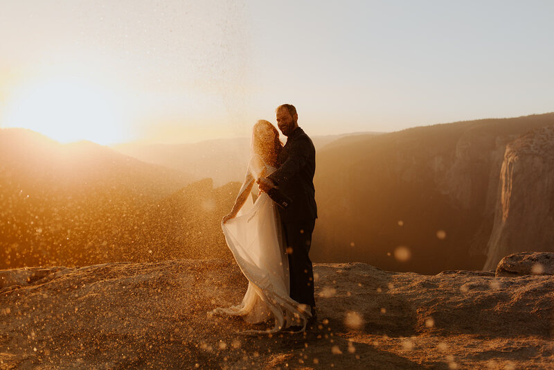 Bride and groom popping champagne at their ceremony at taft point yosemite on their elopement day