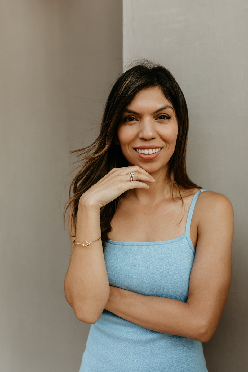 a confident smiling woman in a blue dress