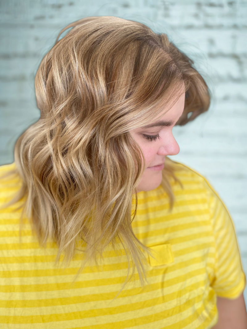 Woman with medium length, curled, auburn hair in the salon.