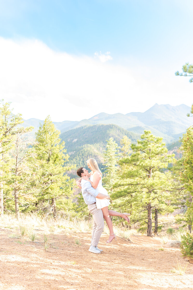 Groom lifting up his bride for a beautiful mountain landscape portrait in Colorado Springs