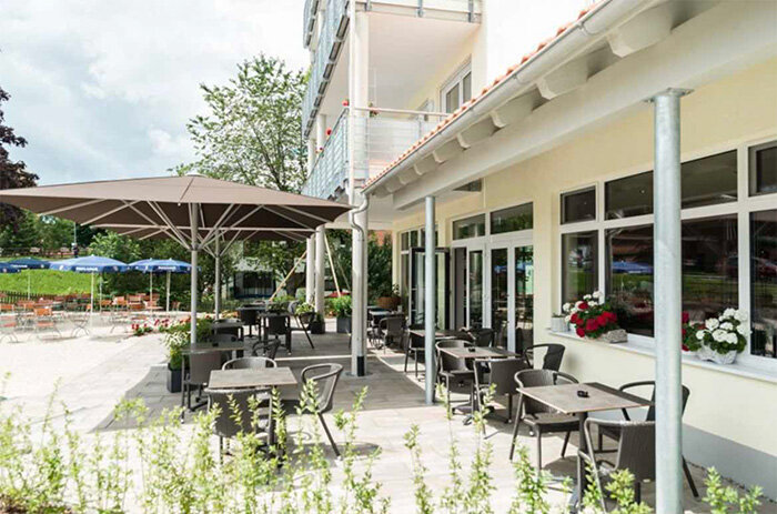 Gemütlicher Gastgarten mit großem Sonnenschirm im Café Zur Alten Schule in Lechbruck am See