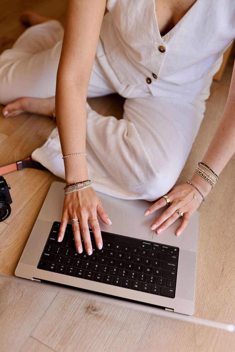 Woman in white sweater and jeans holding laptop