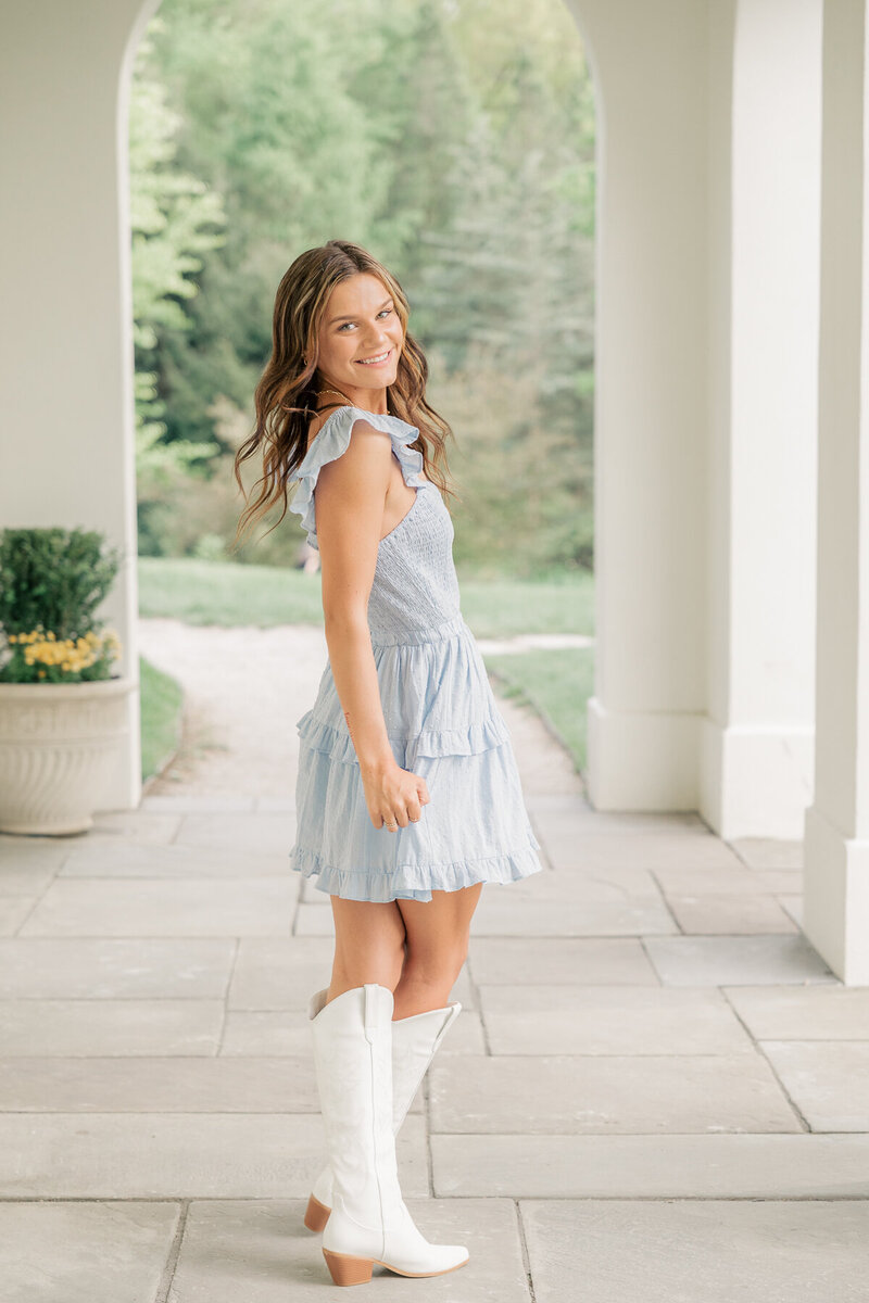 senior girl in light blue dress turns while smiling towards the camera at Newfields, Indianapolis senior photographer