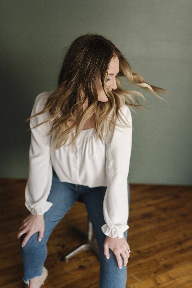 a woman casually dressed seated on a stool