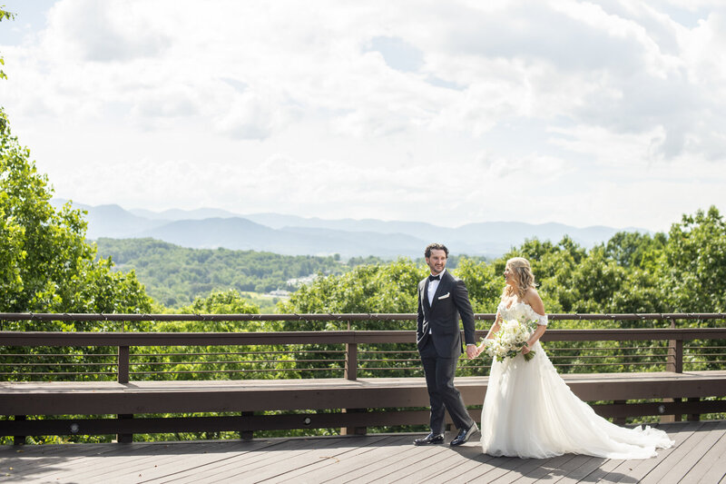 Couple walking with mountains behind at Crest Pavilion Asheville wedding
