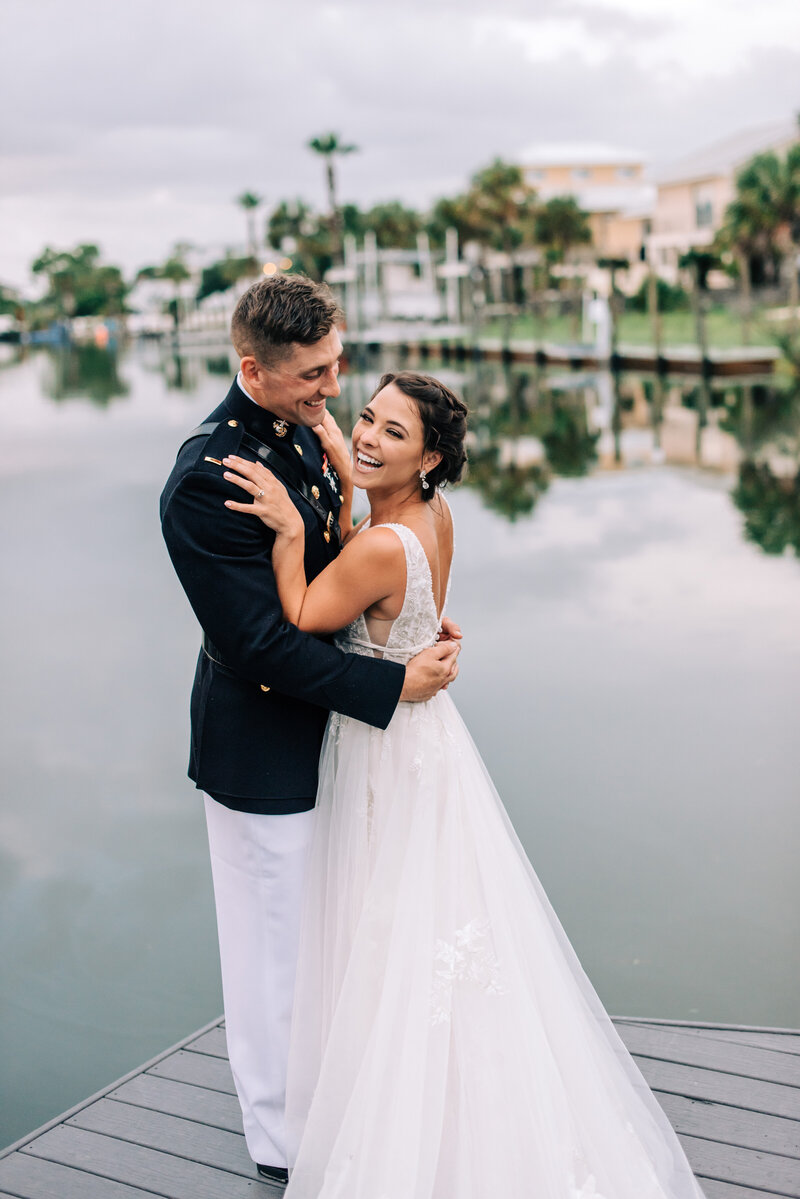 Bride and groom standing on a dock laughing on their wedding day in San Diego