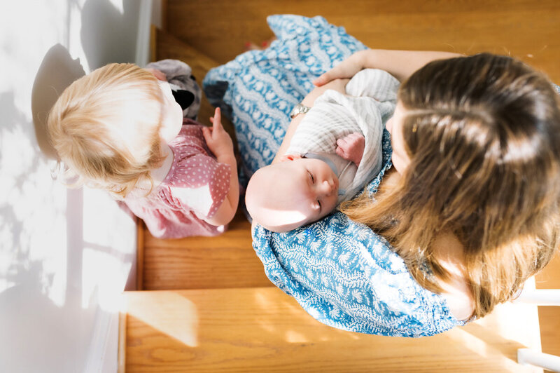 mom holding baby with toddler