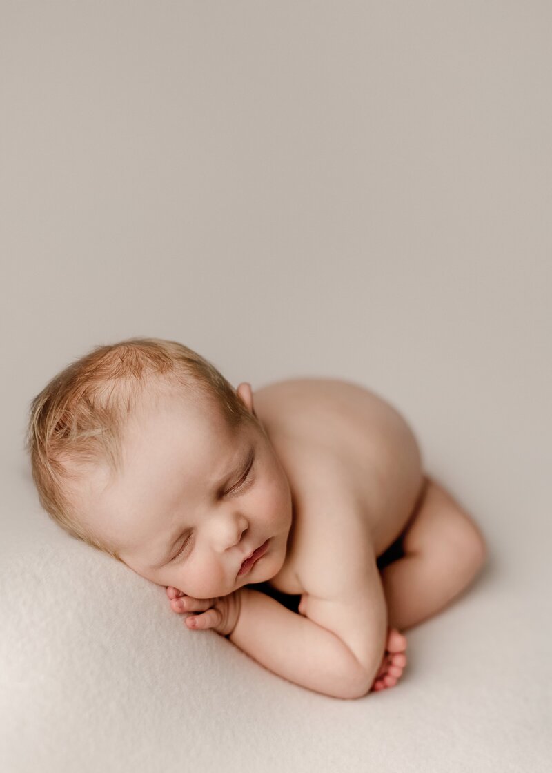 baby posed posed on a cream fabric in our fort newborn photography studio at 5 days old