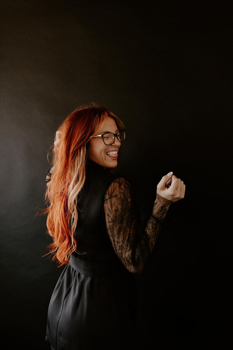 woman with red hair smiling in a lace top