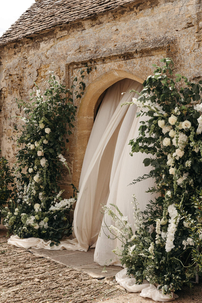 Romantic outdoor ceremony archway with soft drapery at Caswell House, Cotswold wedding venue