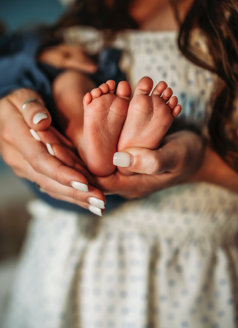 Mom to be and dad to be walk in field holding hands looking at each other lovingly. 