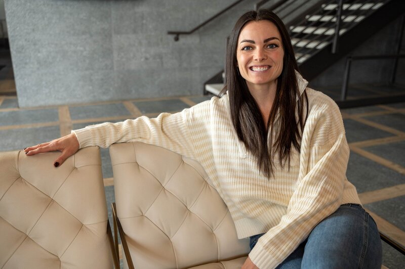 A woman seated on a white couch in a professional office setting, representing a Functional Nutritionist in Denver, CO.