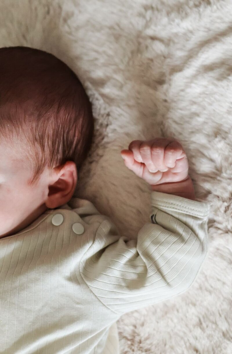 pasgeboren hoofdfoto terwijl de handen dicht bij elkaar zijn in witte kleding 