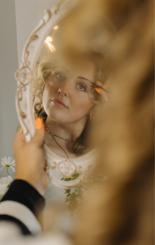 Branding photos and portrait photography of a girl putting on fake eyelashes looking in a mirror.