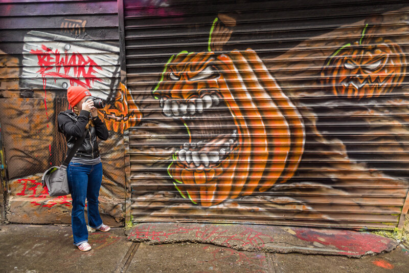 Jen Stitt standing at a vibrant graffiti-covered secret location, creating artistic and edgy moments for a unique engagement session, perfectly blending creativity with a touch of urban charm.