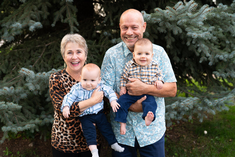 Grandparents hold their two grandsons during their family pictures.