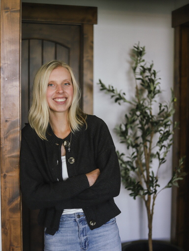 Portrait of interior designer Kaitlyn Schultz smiling in a bright, modern home.