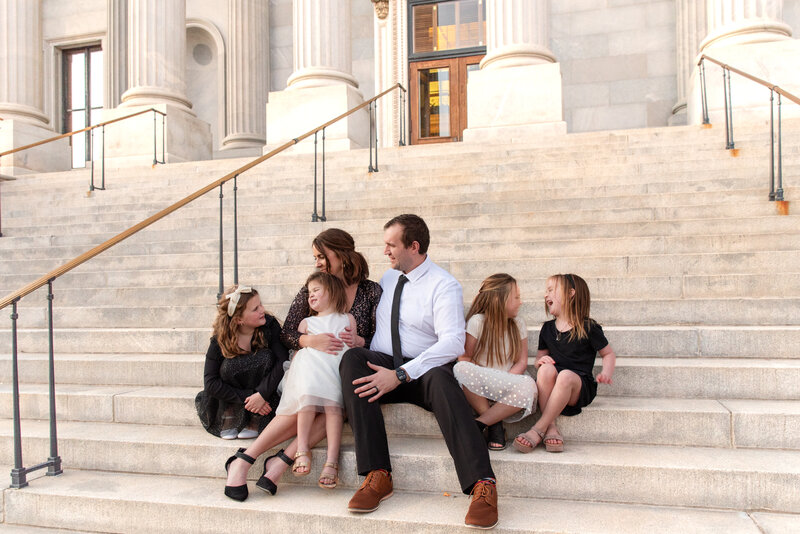 Family all looking at each other sitting on stairs during a family photo session.