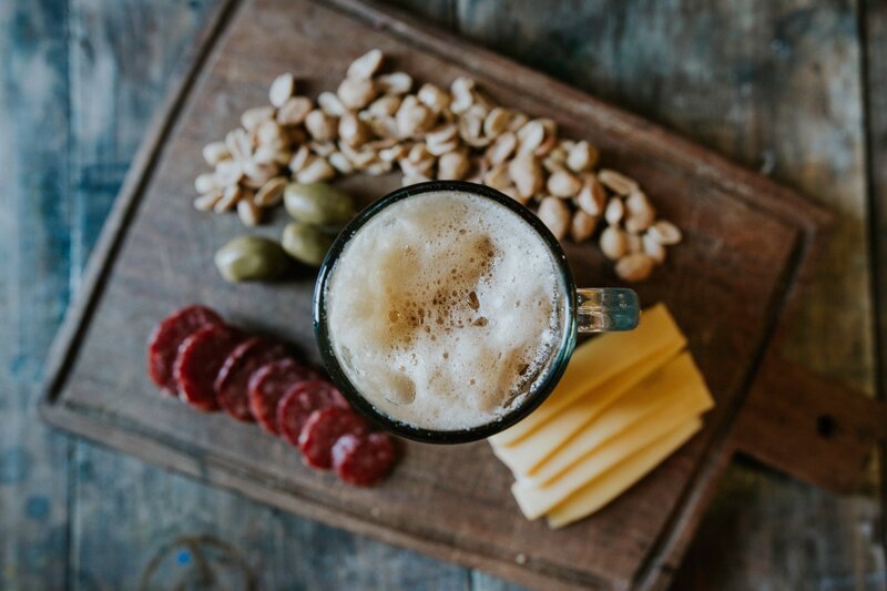 Meat and cheese board with a frothy beer glass.
