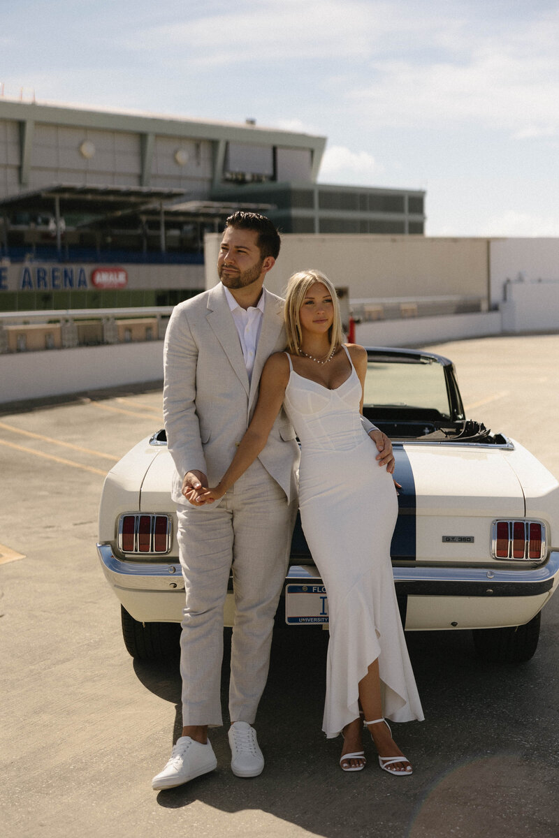 couple on top of a parking garage with a classic car