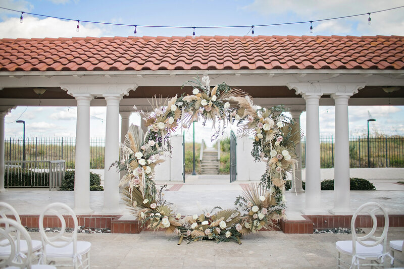 Dramatic circular floral installation for a coastal ceremony backdrop, a signature design by St. Augustine wedding planner The Eventful Gals.