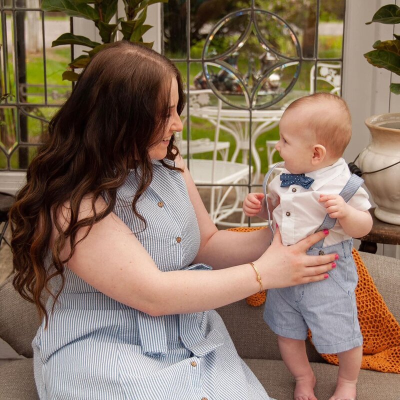 Genasys, blogging coach and founder of Boss Lady Bloggers, smiling at her toddler while sitting outside in a blue dress — representing the heart behind the business and the balance of motherhood and entrepreneurship